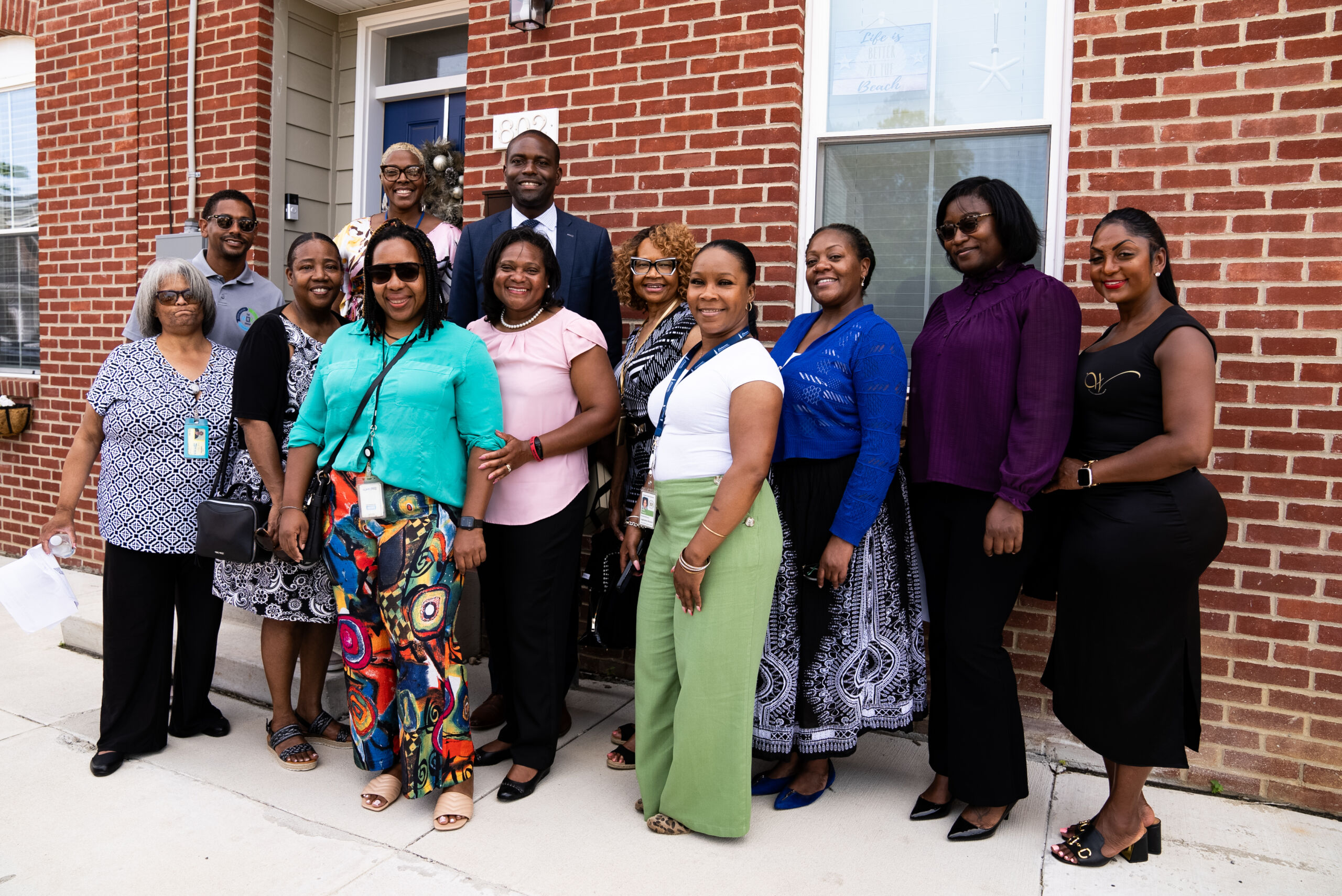 Group of people posing outside brick building.