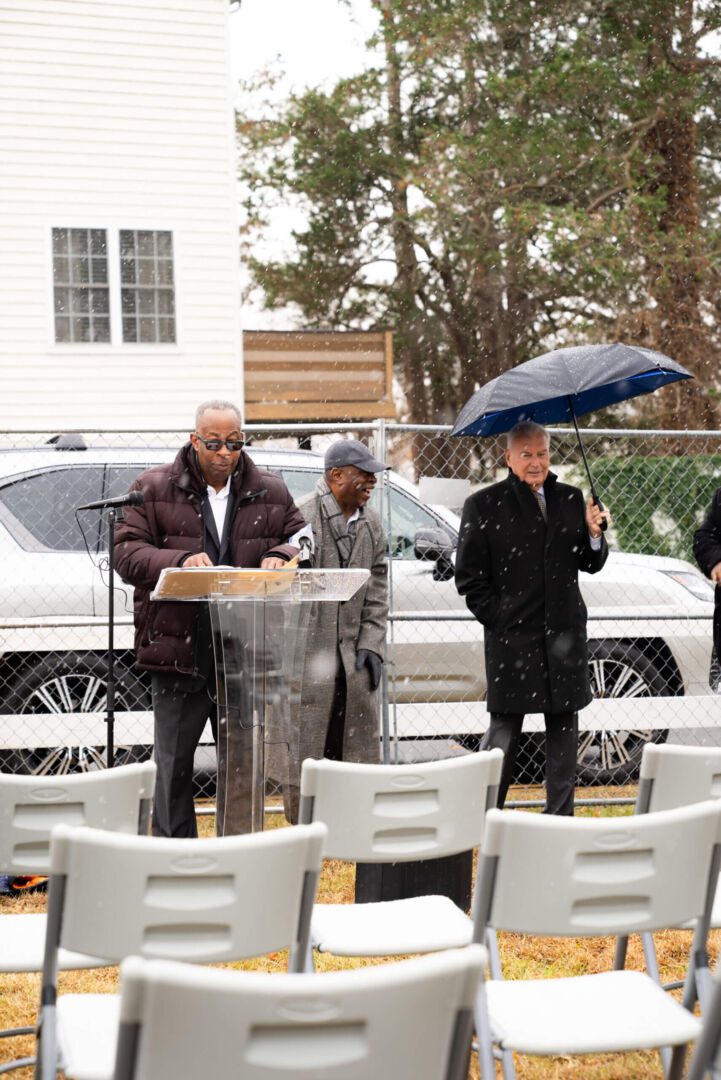 A person speaking on the mike in a funeral with chairs in the front