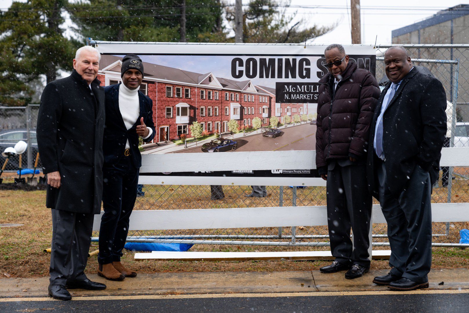 A group of people standing near a coming soon board